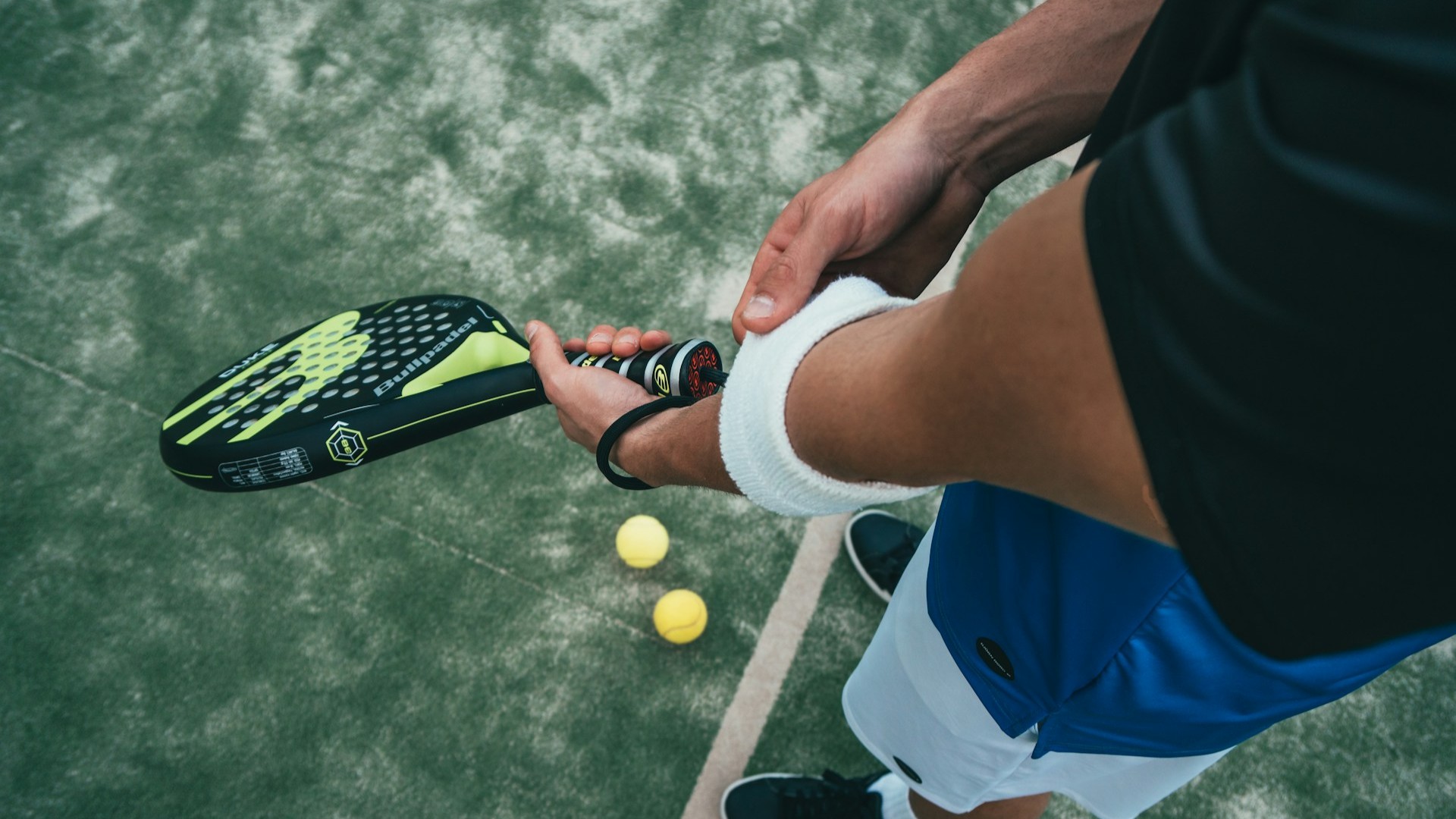 Speler bereidt zich voor op een padelwedstrijd met racket en ballen op de baan