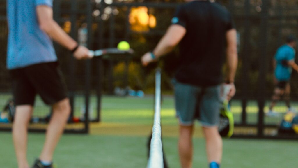 Twee padelspelers begroeten elkaar aan het net voor aanvang van de wedstrijd
