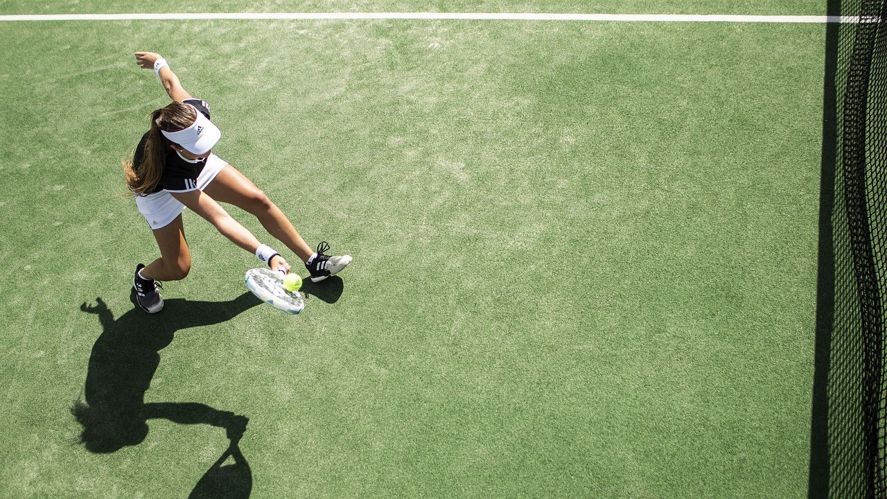 vrouw die een bal slaat op een padelbaan