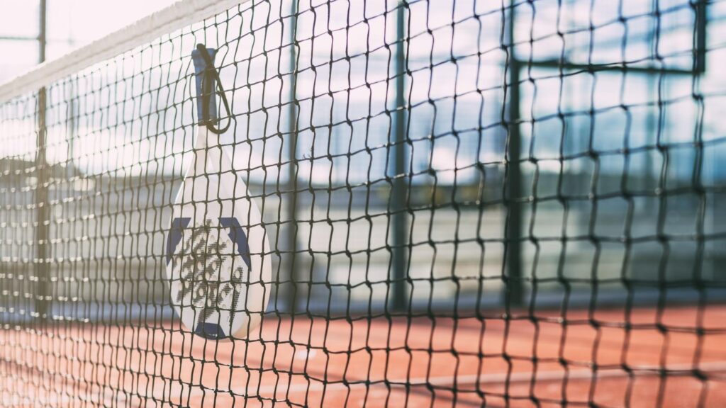 Padelracket hangt aan het net op een buitenbaan, symbool voor de digitale groei via Padel Now