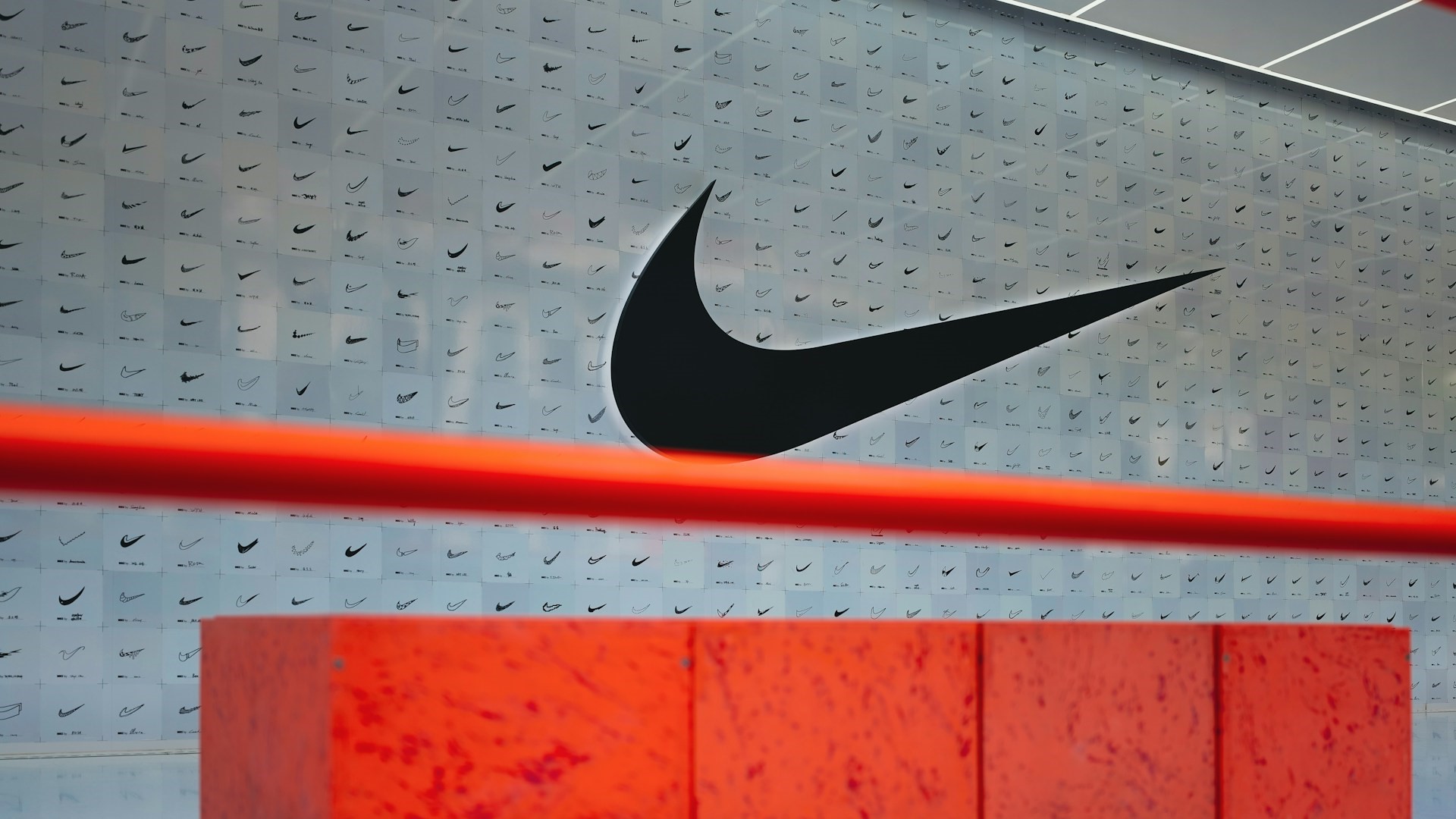 Nike muurdisplay met verschillende swoosh-logo’s en groot zwart Nike logo op de voorgrond