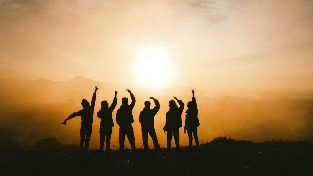 Silhouetten van jongeren tijdens zonsondergang op sportieve vakantie, samen in een ontspannen moment