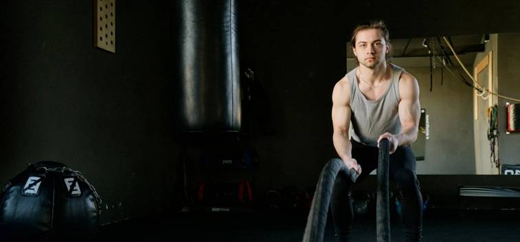 Man traint zijn reactievermogen met battle ropes in een donkere sportschool